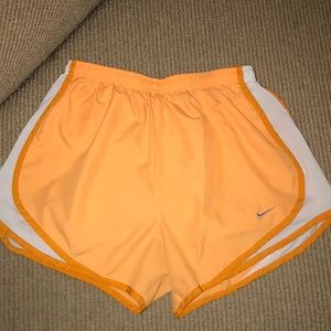 Orange Nike shorts with white sides. Size small.